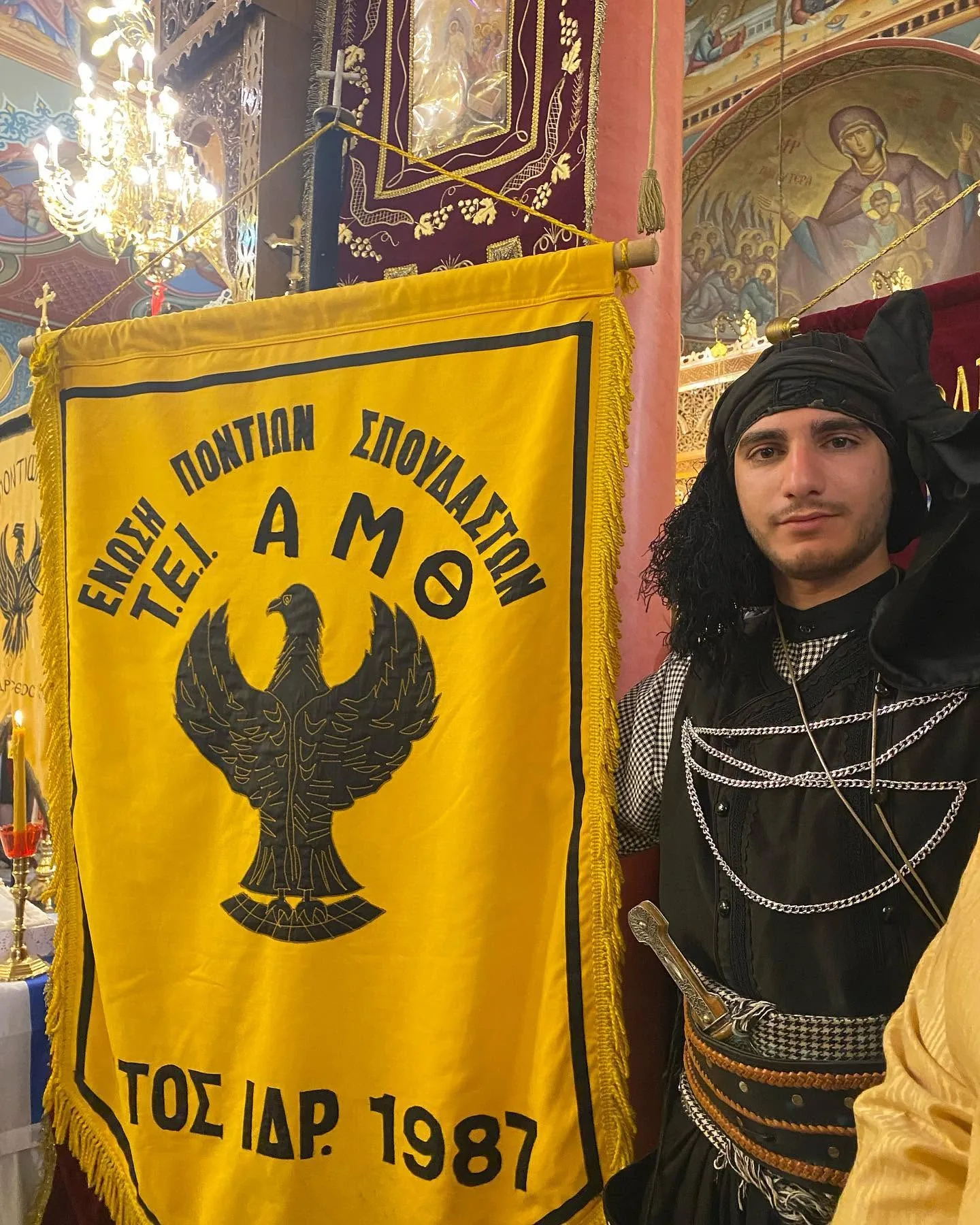 Μέλη με παραδοσιακή στολή και λάβαρο έξω από εκκλησία