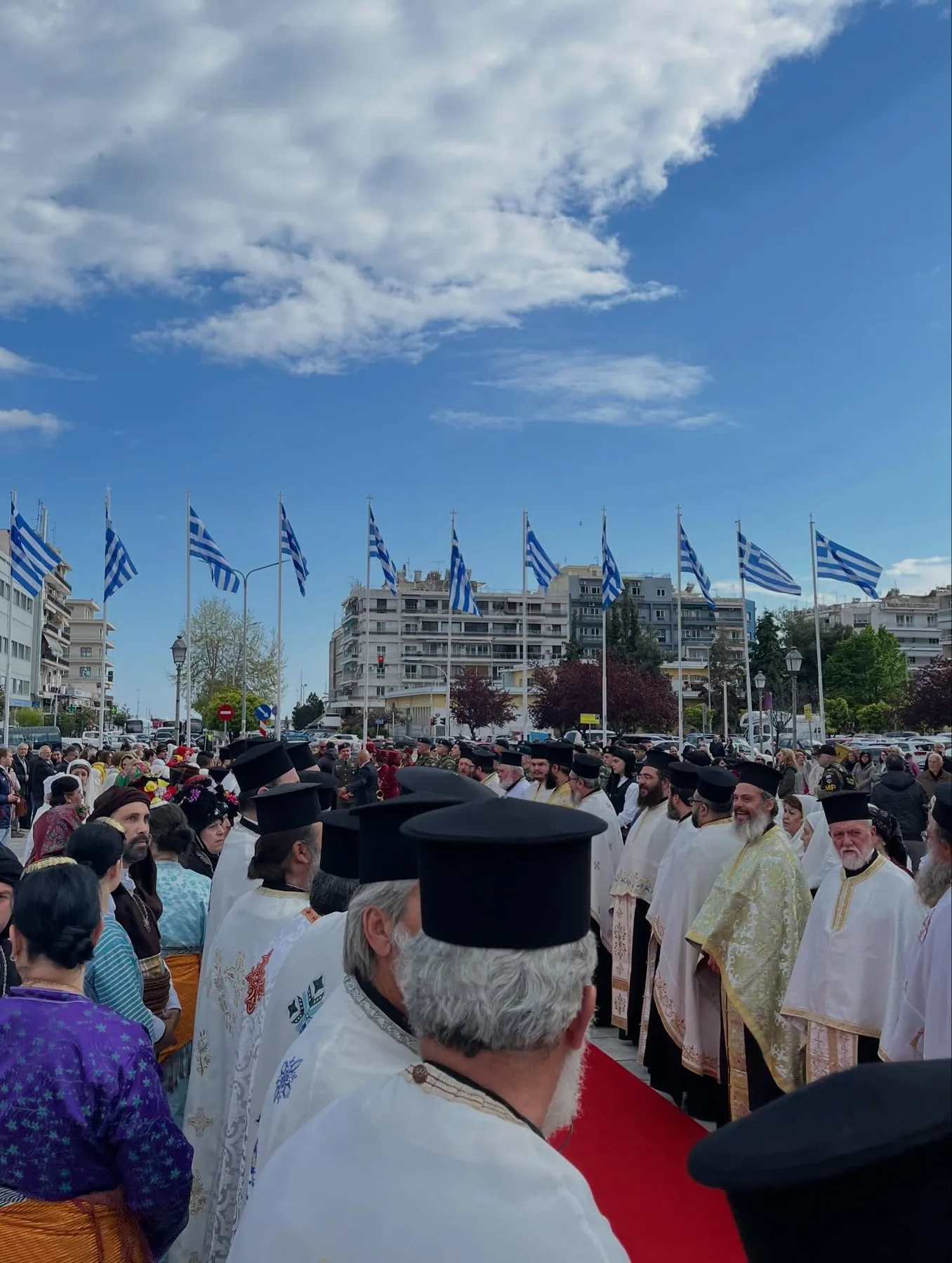 Ιερείς και ελληνικές σημαίες σε πομπή